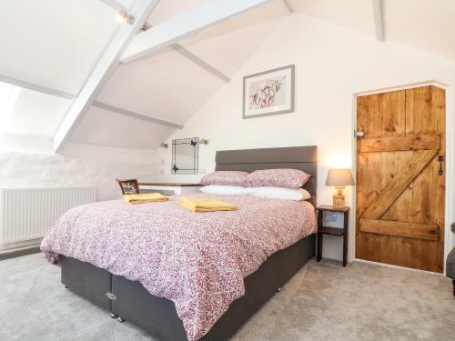 a bedroom with a large bed and a wooden door at The Barn at Trevothen Farm in Helston
