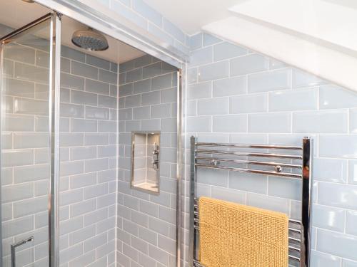 a bathroom with a shower with blue tiles at The Barn at Trevothen Farm in Helston