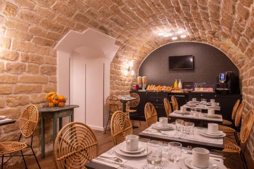 restauracja ze stołami i krzesłami oraz ceglaną ścianą w obiekcie Hôtel Istria by Magna Arbor w Paryżu