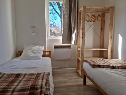 エグルトンにあるHôtel Eden Lakeのベッド2台と窓が備わる小さな客室です。