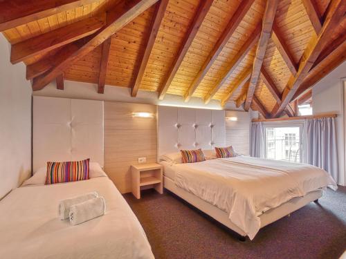 1 dormitorio con 2 camas y techo de madera en @ Home Hotel Locarno, en Locarno