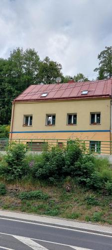 ein Haus mit rotem Dach am Straßenrand in der Unterkunft Apartmány Arin in Jáchymov