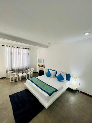 a bedroom with a large white bed with blue pillows at Sunset Sands in Hikkaduwa