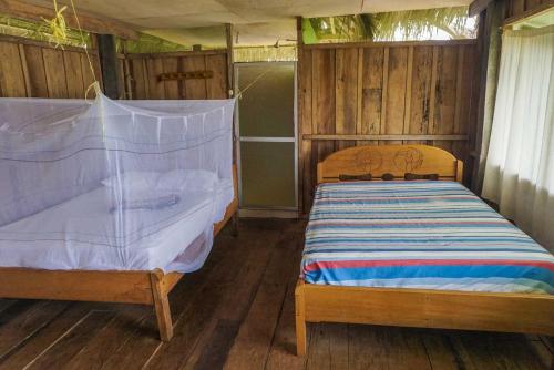 - une chambre avec 2 lits dans une pièce dotée de murs en bois dans l'établissement Libertad Jungle Lodge, à Yucuruche