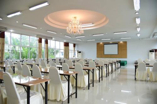 a conference room with tables and chairs and a screen at Tuscany Hotel by skypark 
