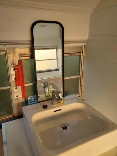 a bathroom sink with a large mirror above it at The School Bus in Bassenge