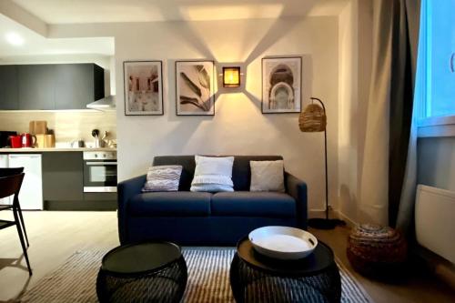 a living room with a blue couch and a kitchen at Le Marrakech Appart' T1 au centre du Mans in Le Mans