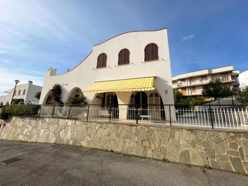 um edifício branco com uma cerca ao lado de uma rua em Casa La Perla - Alloggio con terrazza panoramica, piscina e free parking em Ceriale