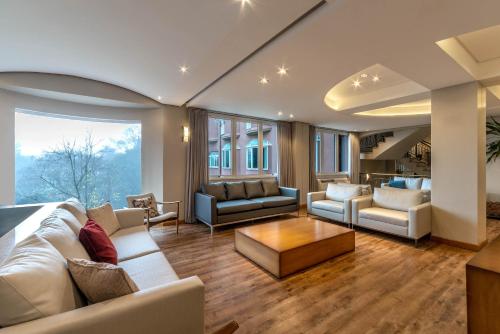 ein Wohnzimmer mit weißen Möbeln und einem großen Fenster in der Unterkunft Hotel Laghetto Siena Gramado in Gramado