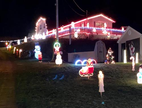 a house covered in christmas lights in a yard at Ingonish Loft in Ingonish