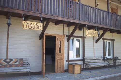 a building with a balcony and a wooden door and bench at Садиба Карпат in Roztoky