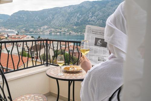 a person sitting on a balcony with a glass of wine at Enyana Luxury Suites in Kotor