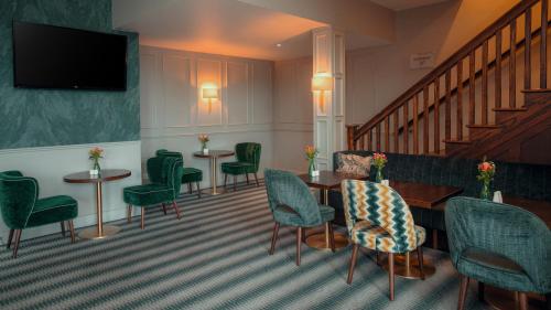 a waiting room with green chairs and tables and a staircase at Cavan Crystal Hotel in Cavan