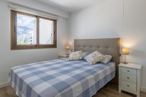 een slaapkamer met een blauw en wit bed en een raam bij Top first line apartment Altea in Altea