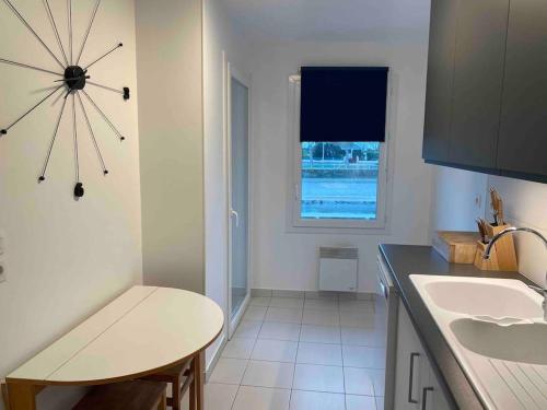 une cuisine avec un évier, une table et une fenêtre dans l'établissement La Libellule by Conciergerie Audrey, à Trouville-sur-Mer