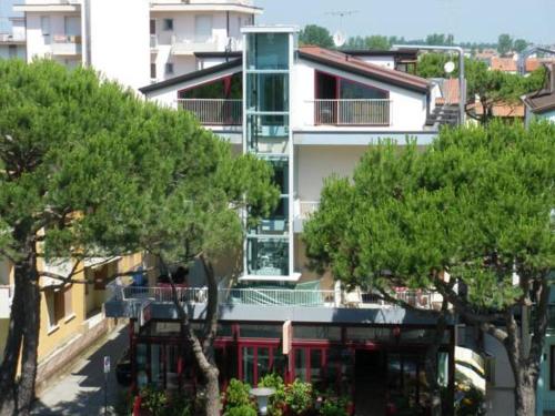 a tall building with trees in front of it at Hotel Villa Dina in Lido di Jesolo