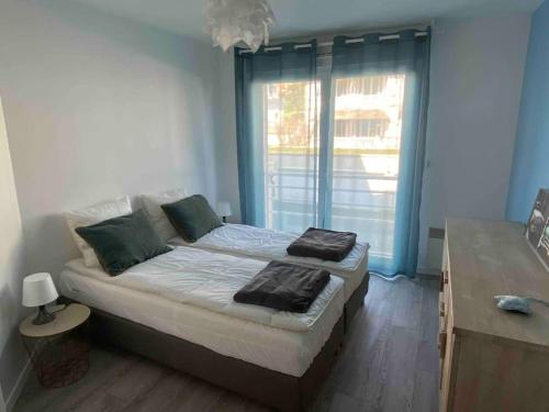 un lit dans une chambre avec une grande fenêtre dans l'établissement La Libellule by Conciergerie Audrey, à Trouville-sur-Mer