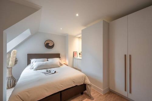 a bedroom with a large bed with white walls at Morgenzon luxueus appartement in Knokke-Heist