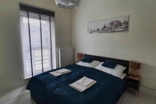 a bedroom with a blue bed with two towels on it at Abstractive Apartament Spokojna in Wisła