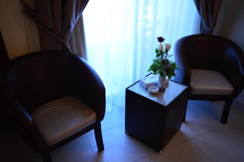two chairs and a table with a vase of flowers at Ream Hotel Amman in Amman