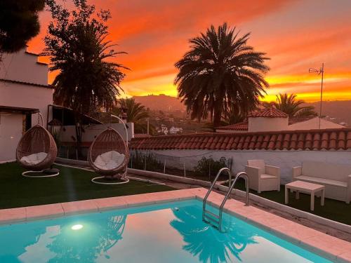 a swimming pool with a sunset in the background at Hotel Rural Villa del Monte in Santa Brígida