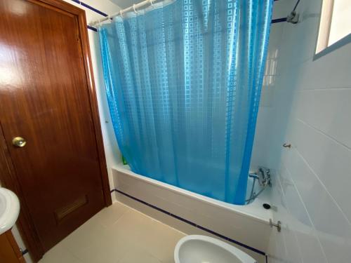 ein Bad mit einem WC und einem blauen Duschvorhang in der Unterkunft ESPACIO Y LUZ en Isla Cristina Capacidad hasta 8 HUESPEDES in Isla Cristina