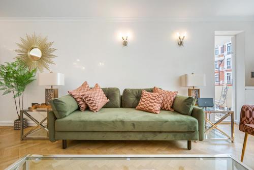 una sala de estar con un sofá verde con almohadas en Flat 9 en Londres