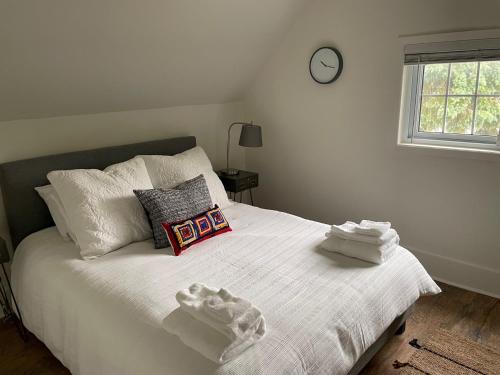 a bedroom with a white bed with a clock on the wall at Welcome to The Flats Hotel North Suite in Wellington