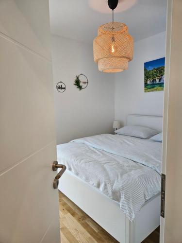 a white bedroom with a bed and a hanging light at Old Town Đurđevac- 1 garažno mjesto, besplatan wifi te ulaznice za Hrvatsku saharu, mini zoo in Ðurđevac