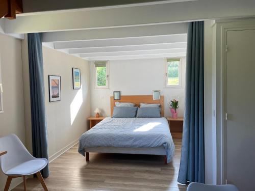 a bedroom with a bed and two chairs in it at Cottage YVEL au Pied du lac au Duc, son Golf et sa Base Nautique in Ploërmel