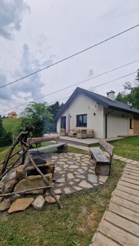 ein Haus mit einer Bank und einer Steinterrasse in der Unterkunft Dom wypoczynkowy jednorodzinny całoroczny in Bobowa