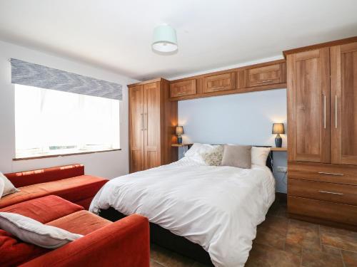 a bedroom with a bed and a red couch at 50 Harbour Road in Bognor Regis