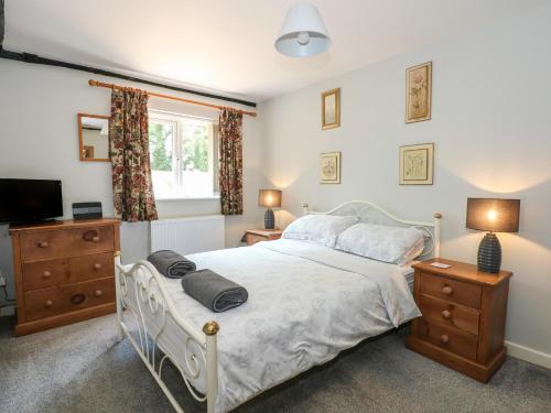 a bedroom with a white bed and a television at Hadleigh Farm Cottage in King's Lynn