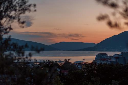 a sunset over a city and a body of water at Aria di Mare Apartments in Tivat