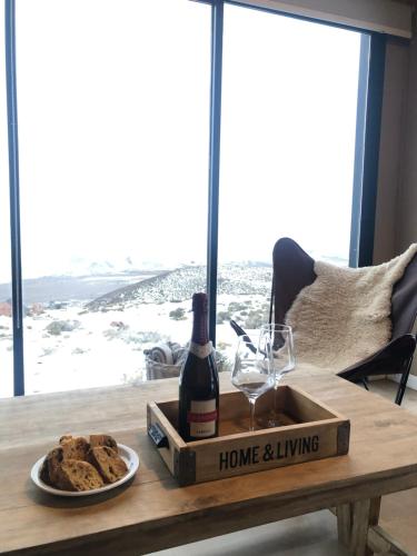 een tafel met een fles wijn en een bord koekjes bij Cabañas de Montaña Armonías Lodge in Los Molles