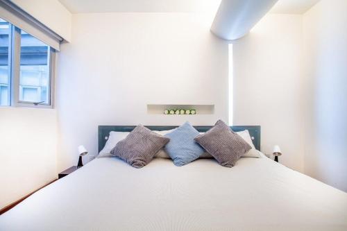 um quarto com uma grande cama branca e 3 almofadas em La mejor ubicación con alberca caliente, gym, bar em Cidade do México