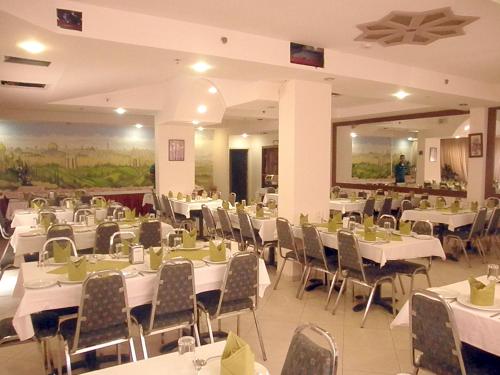 un salón de banquetes con mesas y sillas blancas en Commodore Hotel, en Jerusalén