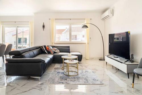 a living room with a black leather couch and a tv at Cascais Garden Villa in Cascais