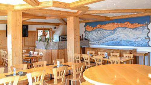 ein Restaurant mit Holztischen und -stühlen und einem Wandbild in der Unterkunft Hotel Aletschhorn in Belalp