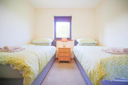 two twin beds in a room with a window at Glenview Chalet Park in Inverness