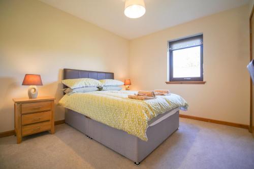 Glenview Chalet Park في إينفيرنيس: غرفة نوم مع سرير مع منضدة ونافذة