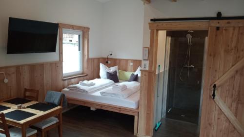 a bedroom with a bed with a television and a shower at Belzesaltescheune Heuboden Rhön in Riedenberg