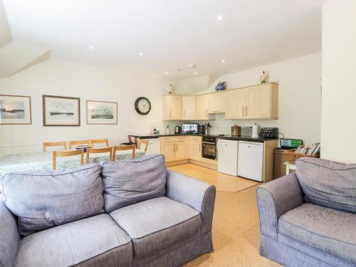 a living room with two couches and a kitchen at The Mews Flat in Dalswinton