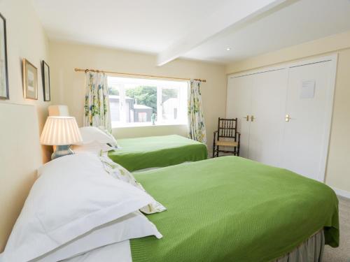 two green beds in a room with a window at The Mews Flat in Dalswinton