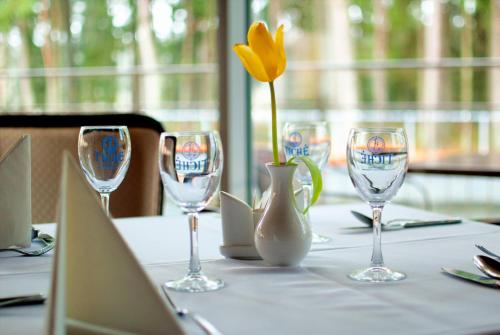 a table with wine glasses and a vase with a yellow flower at Royal SPA Residence in Birštonas