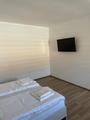 a room with a bed with white sheets and a tv at Casa Marko in Nădlac