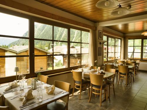 ein Restaurant mit Tischen und Stühlen und großen Fenstern in der Unterkunft Hotel Massa in Blatten bei Naters