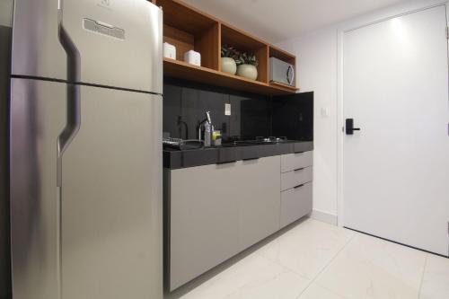 a kitchen with white cabinets and a refrigerator at Unity #110 - Apartamento ao mar por Carpediem in Penha