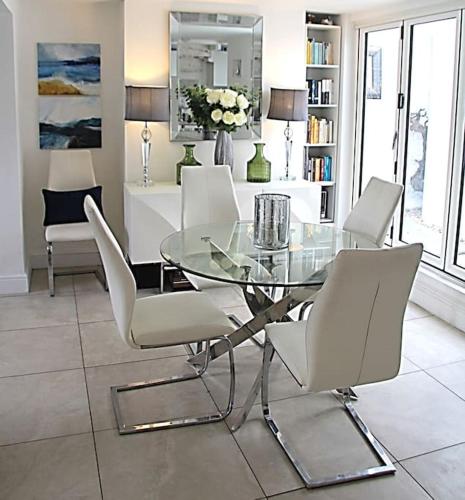 a dining room with a glass table and white chairs at Sommersway Cottage in Brixham