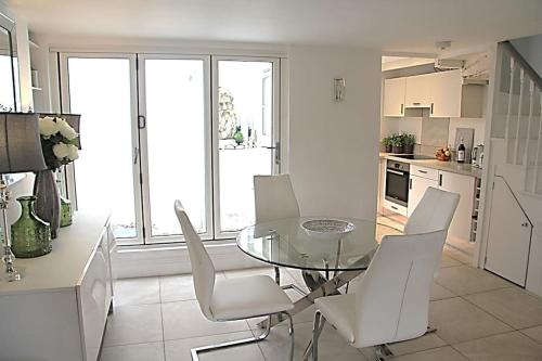 une cuisine avec une table en verre et des chaises blanches dans l'établissement Sommersway Cottage, à Brixham
